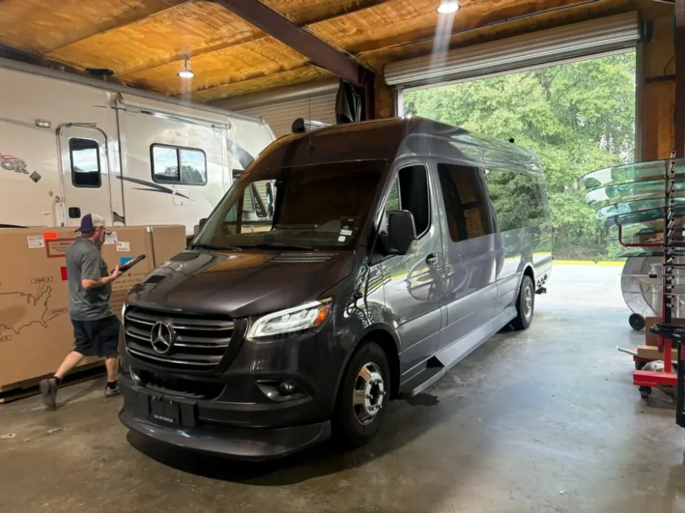 A high-roof van in the Absolute Auto Glass workshop, with a Class C motorhome in the background.